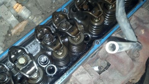 1988 Ford Bronco - The image shows the internal components of an engine, specifically the rocker arms and valve springs, covered in oil. A blue valve cover ga…