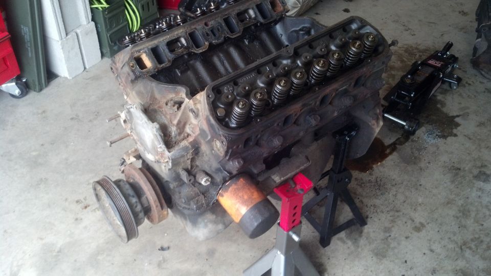 V8 engine block on jack stands with oil on the floor.