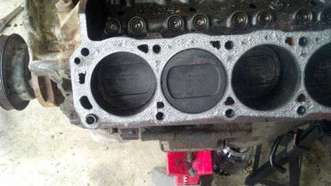 1988 Ford Bronco - Close-up view of the cylinder head gasket and pistons on a Ford engine block. The engine is supported by a red jack stand and appears to be…