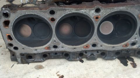 1988 Ford Bronco - A close-up view of a V8 engine block's cylinder head with four cylinders visible. The cylinders show signs of carbon buildup and two valves…