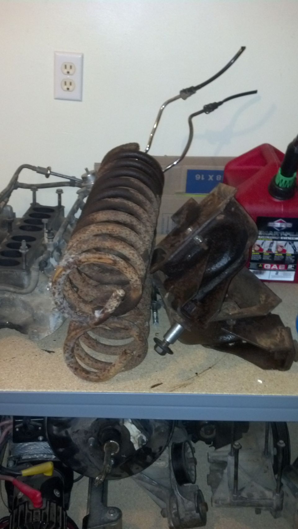 Two rusted coil springs and a suspension part on a workbench.