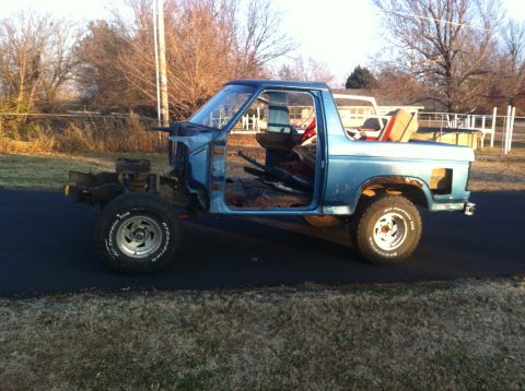 1982 Ford Bronco - This blue pickup truck features a white bed and is viewed from its side profile.