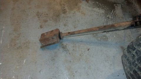 1988 Ford Bronco - A rusty metal component rests on a concrete surface, with a tire visible on the right side.