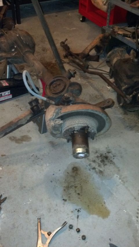 1988 Ford Bronco - Vehicle axle and suspension components are laid out on a workshop floor, suggesting a repair or rebuild.