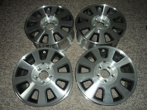 2004 Mercury Grand Marquis - Four silver alloy wheels with black accents are laid out on a carpeted floor. The wheels appear to be aftermarket or custom replacements fo…
