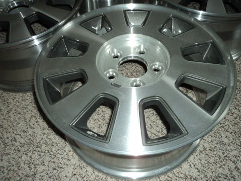 2004 Mercury Grand Marquis - A close-up, angled shot shows a set of four silver alloy wheels with black accents, resting on a carpeted surface. The wheels have a multi-…