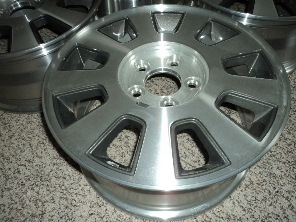 Silver alloy wheels with black accents on a carpeted surface.