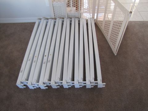 1995 Ford Bronco - A collection of white baby gate panels are laid out on a carpeted floor, with a white wall and baseboard visible in the background.