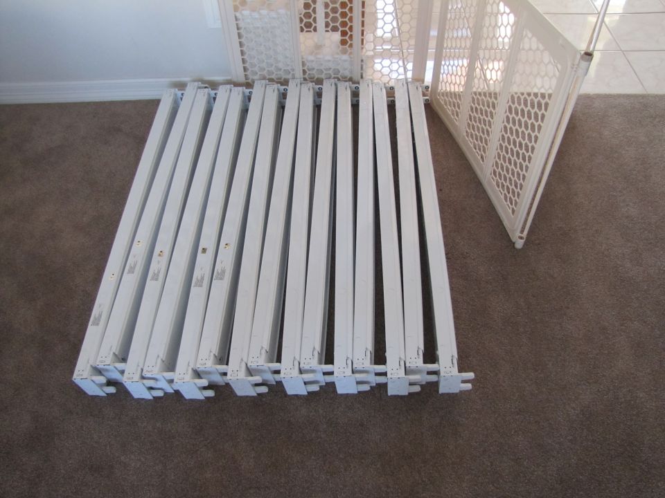 White baby gate panels laid out on a carpeted floor.