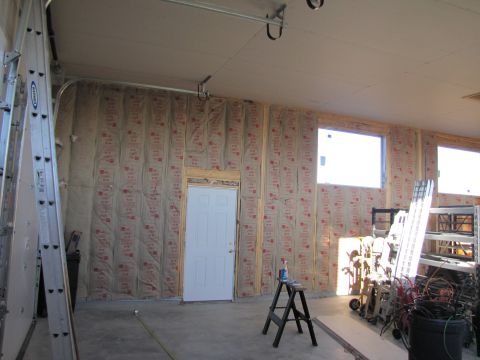 1995 Ford Bronco - The image shows the interior of a garage or workshop under construction. The walls are insulated, and there is a white door, two windows, a…