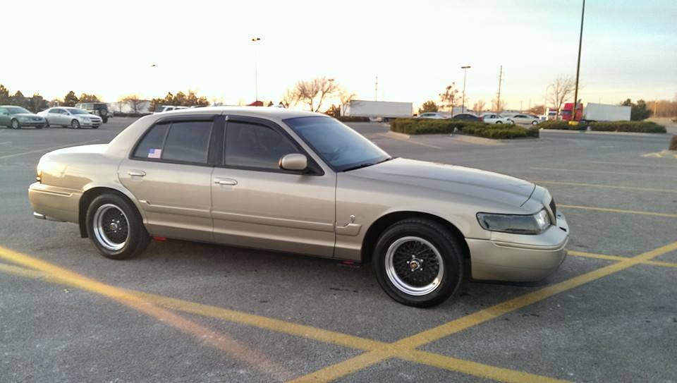 Side profile of a gold Mercury Grand Marquis sedan in a parking lot