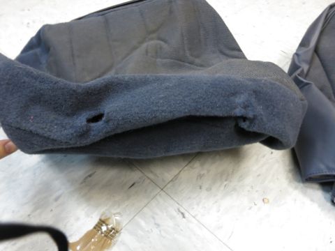 2001 Ford Crown Victoria - A close-up view of a damaged car seat cover, showing wear and tear on the fabric.