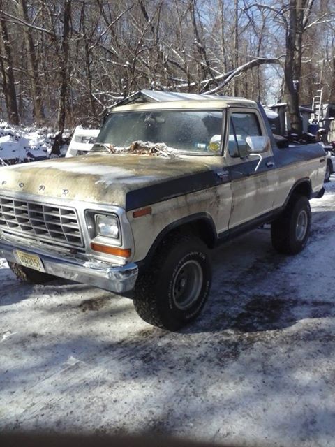 1979 Ford Bronco - A weathered Ford Bronco sits in a snowy, wooded area.