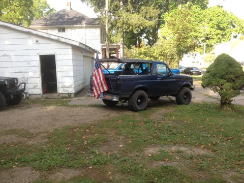 1996 Ford Bronco - Dark blue 1996 Ford Bronco parked in a driveway with an American flag on the back.