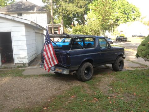 1996 Ford Bronco - This Ford Bronco is parked in a driveway next to a garage, with an American flag attached to the rear.