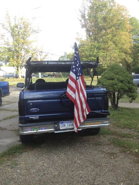 1996 Ford Bronco - This blue SUV is seen from the rear, flying an American flag and displaying license plate CHN 7444.