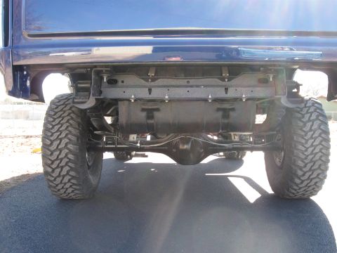 1982 Ford Bronco - Rear view of a blue SUV's undercarriage, showing the axle and suspension components.