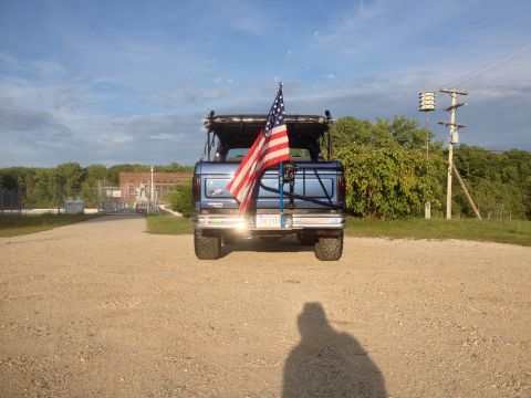 1996 Ford Bronco - Rear view of a blue 1996 Ford Bronco with an American flag mounted on a rack.