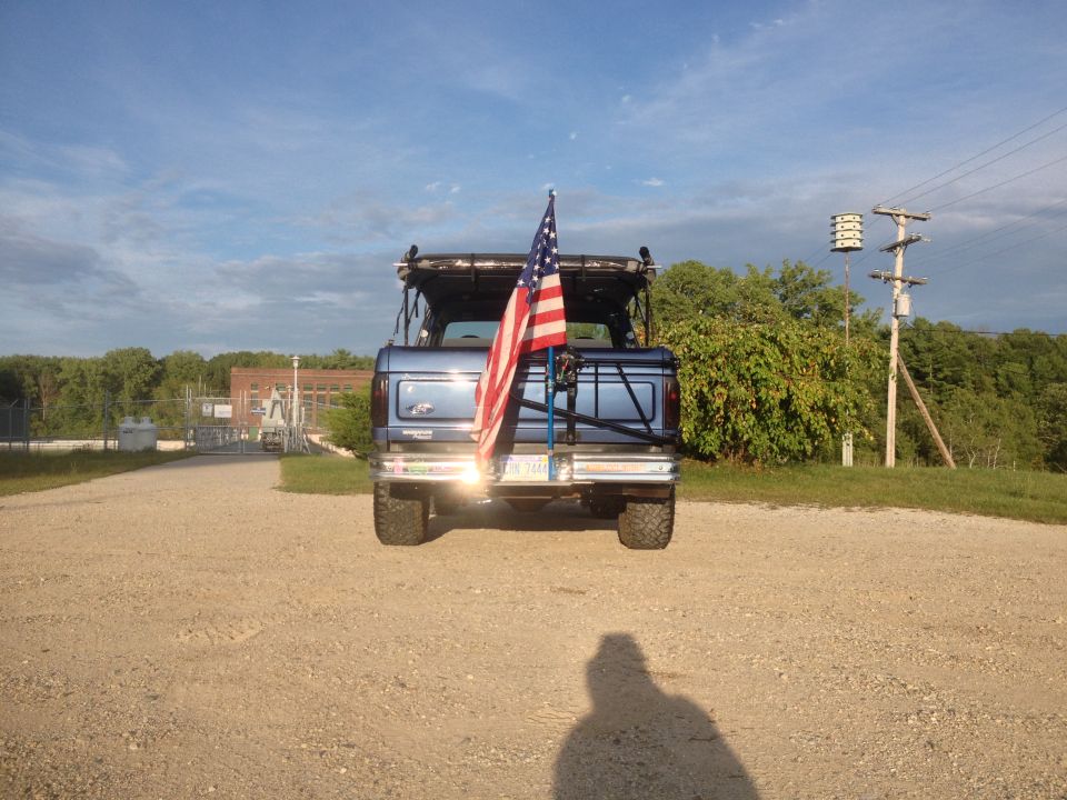 Rear view of blue SUV with American flag mounted on spare tire carrier