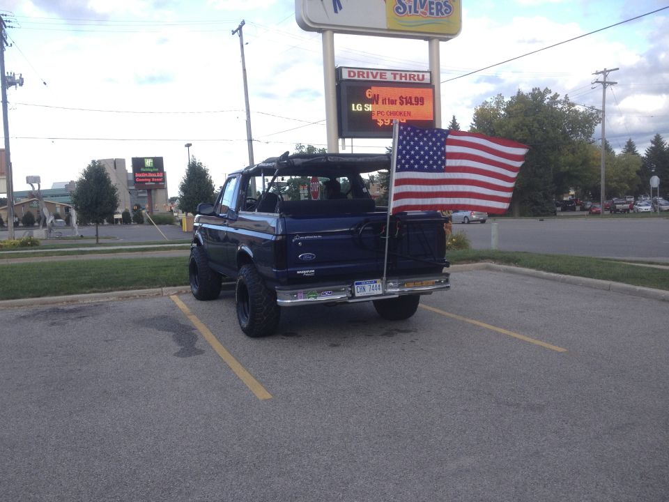 1996 Ford Bronco parked in lot, American flag on rear