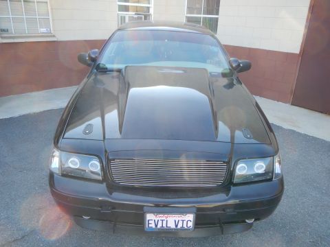 2003 Ford Crown Victoria - Front view of a black Ford Crown Victoria with a raised cowl hood and California EVIL VIC plate.