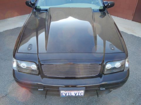 2003 Ford Crown Victoria - View down the contoured hood of a black Ford Crown Victoria toward its billet grille and EVIL VIC plate.
