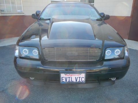 2003 Ford Crown Victoria - Head-on view of a black Ford Crown Victoria with halo headlights and a plate frame reading Crown Victoria above EVIL VIC.