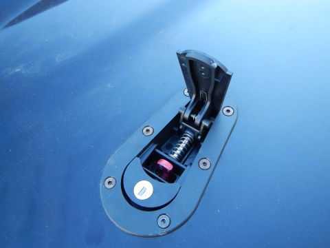 2003 Ford Crown Victoria - Close-up of an open hood-pin latch showing a coil spring and pink-tipped pin on a glossy blue body panel.