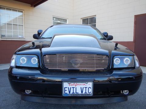 2003 Ford Crown Victoria - Head-on view of a black Ford Crown Victoria with billet grille, halo headlights, and a California EVIL VIC Crown Victoria plate.