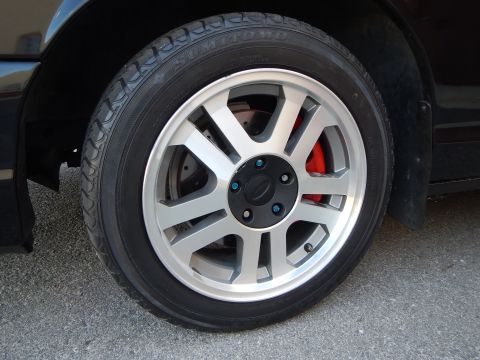 2003 Ford Crown Victoria - Detailed view of a silver seven-spoke alloy wheel with a red brake caliper mounted on a Sumitomo tire.