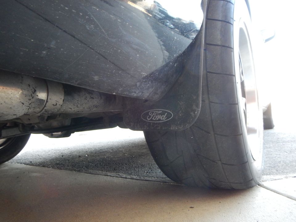 Underside rear of black sedan with Ford mud flap, wide tire and exhaust