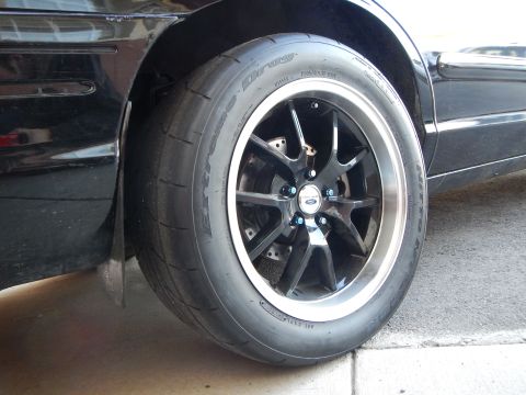 2003 Ford Crown Victoria - Close-up of a black sedan's rear wheel, a black multi-spoke alloy mounted on a Drag-branded tire.