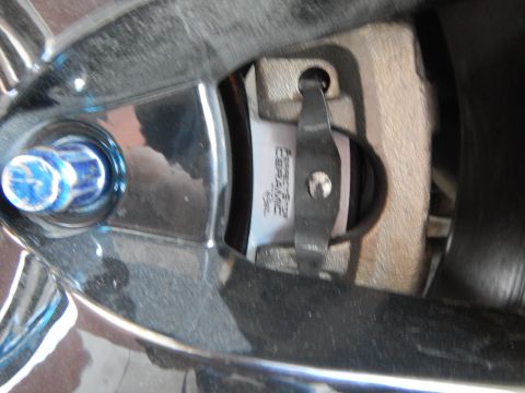 2003 Ford Crown Victoria - brake pad stamped Perfect Stop Ceramic seated in a caliper, photographed at an angle through a chrome wheel spoke.