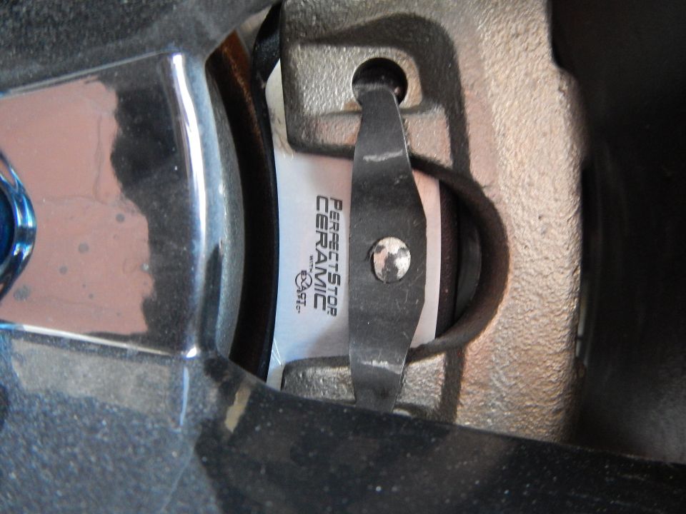 Perfect Stop Ceramic brake pad in caliper seen past a blue lug nut and wheel