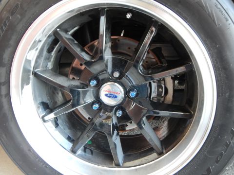 2003 Ford Crown Victoria - glossy black multi-spoke alloy wheel with a polished lip and Ford Racing center cap, mounted over a drilled brake rotor.