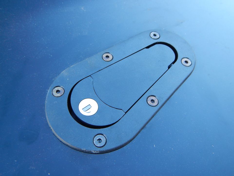 Black oval recessed latch with pull tab mounted in dark blue painted panel
