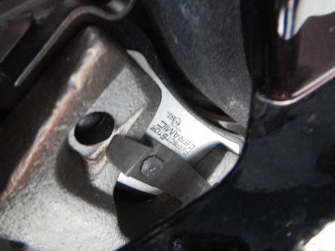 2003 Ford Crown Victoria - Perfect Stop Ceramic brake pad seated in a cast caliper, viewed through the gap of a black wheel spoke.