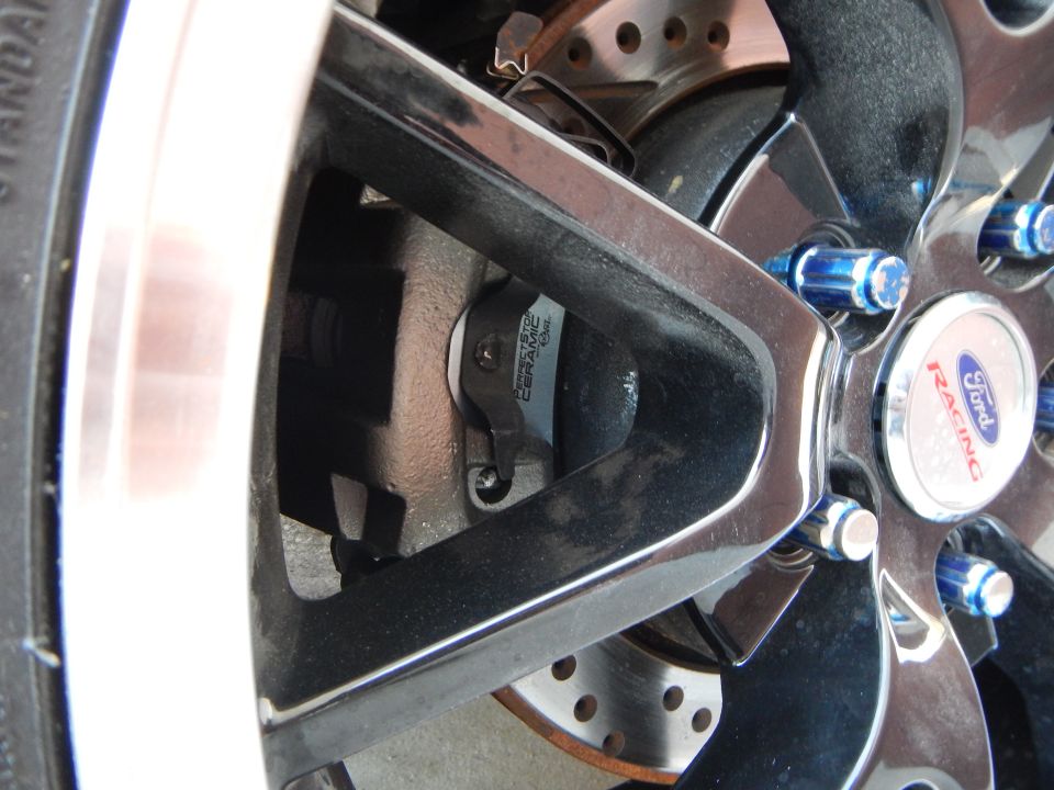 Ford Racing center cap and blue lug nuts on black wheel over drilled rotor