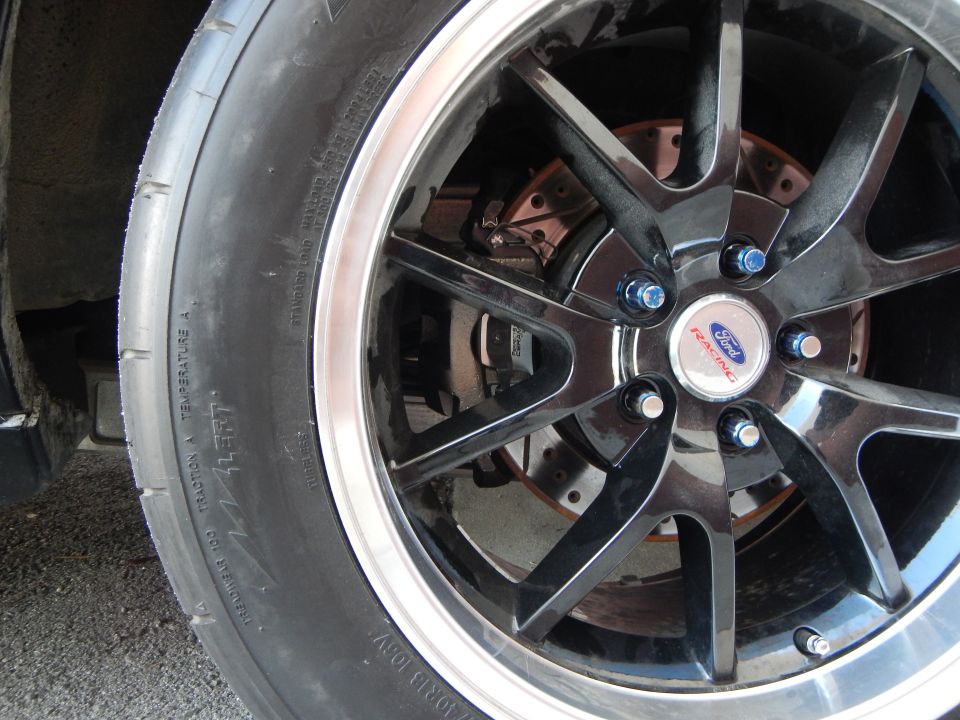 Black machined-lip wheel with Ford Racing cap and blue lug nuts on tire