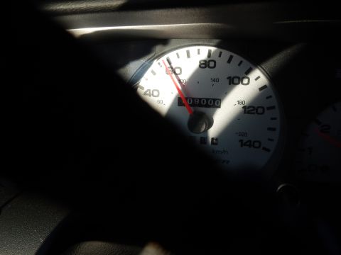 2003 Ford Crown Victoria - sunlit white-faced speedometer reading roughly 09000 on the odometer, with MPH and km/h scales and a red needle.