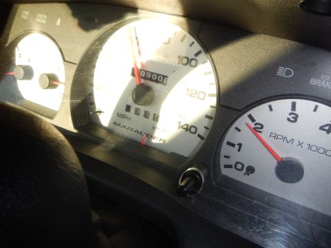 2003 Ford Crown Victoria - Marauder-labeled speedometer reading 09000 on the odometer next to an RPM x1000 tachometer, in bright sunlight.