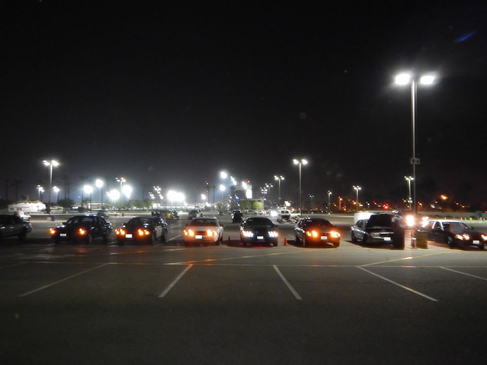 Lineup of sedans parked at night under tall light poles