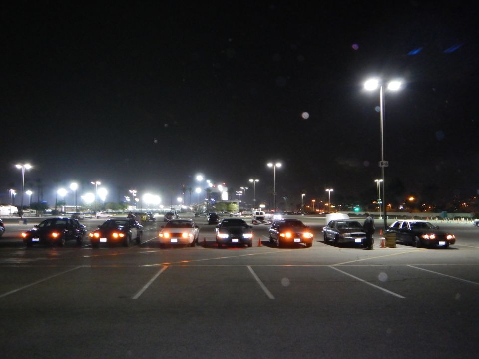 Row of cars with parking lights on in a dark lot at night