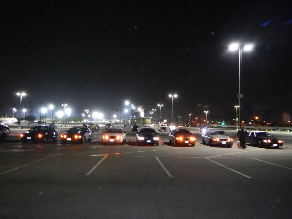 Lineup of sedans at night with a person standing at the end of the row