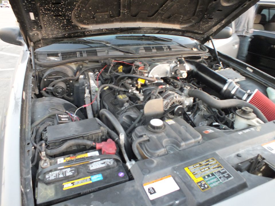 Open hood showing full V-engine bay with battery and red intake filter