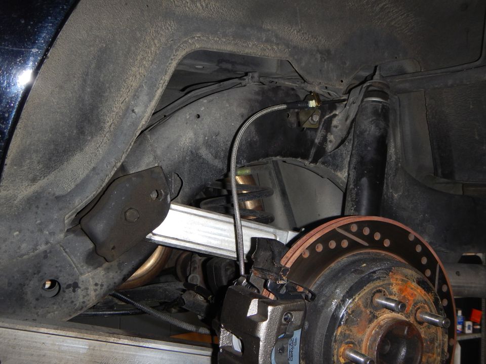 Underside view of a rear suspension showing coil spring, control arm and brake rotor