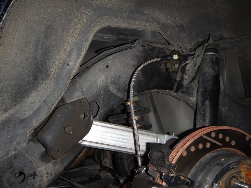 Underbody rear suspension with coil spring, brake rotor and routed brake line