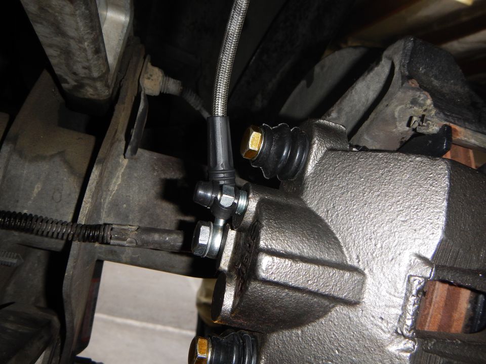 Brake caliper with braided stainless steel brake line attached, underbody view