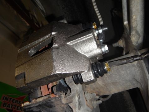 2003 Ford Crown Victoria - close-up of a freshly cast brake caliper with banjo bolts and brake pad, an Interstate Batteries box behind it.