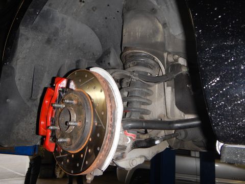 2003 Ford Crown Victoria - underbody view of front suspension showing a coil spring, sway bar and a red caliper on a drilled rotor.